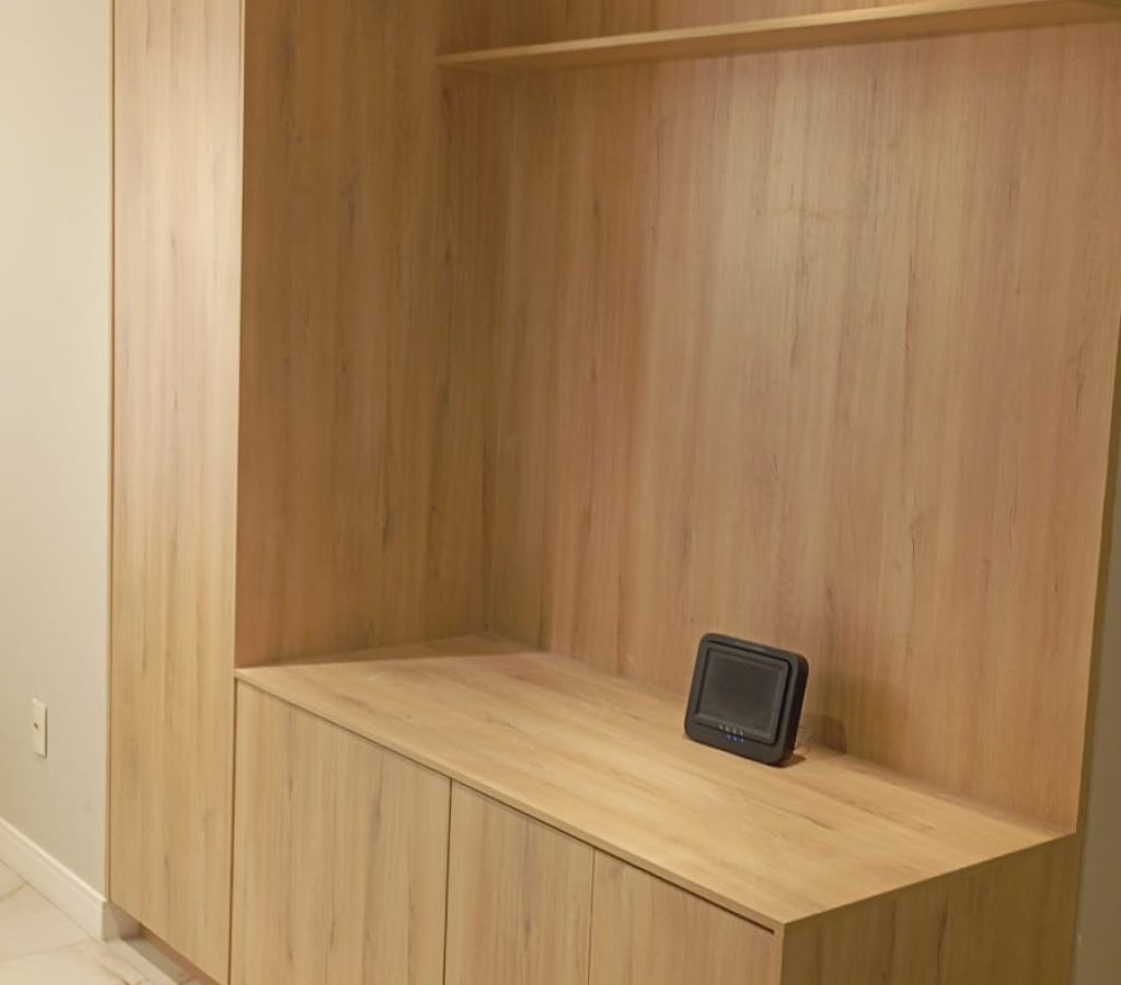 Estante de sala de estar moderna e planejada com várias portas e nichos, feita em MDF com acabamento que imita madeira clara. Projeto Kairós Prime.
